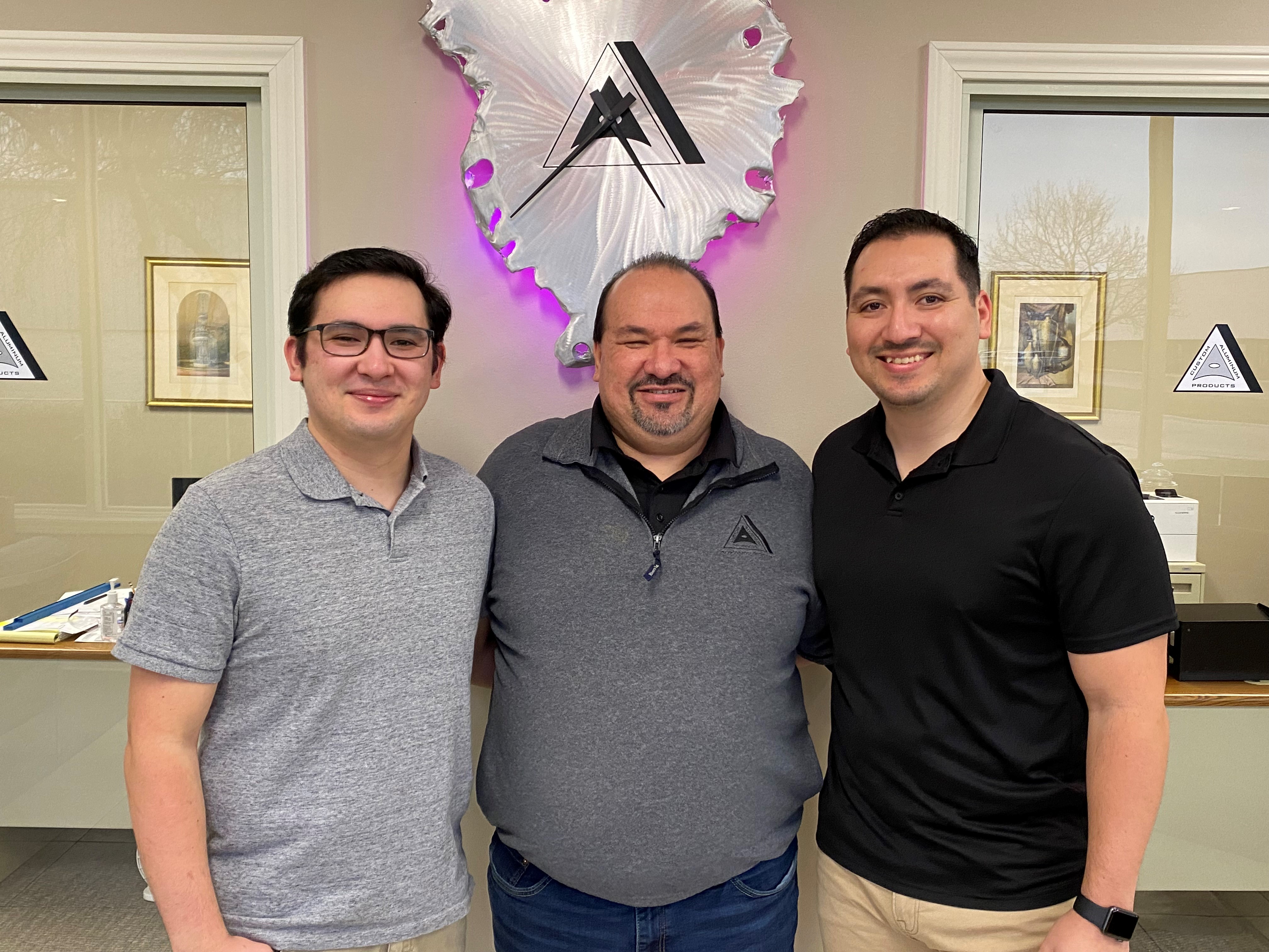 Gilbert Bello started at Custom Aluminum Products racking parts right out of high school 33 years ago. Today, he is Manager of Quality and Compliance. His son, Ivan (right), worked at Custom for a decade. His younger son, Brandon (left), still works there as does his nephew Francisco. Gilbert worries about the impact of unfairly priced aluminum extrusions from China and elsewhere. “Everything that I have and that my family has is because of Custom Aluminum,” he said. “I’m definitely scared.”